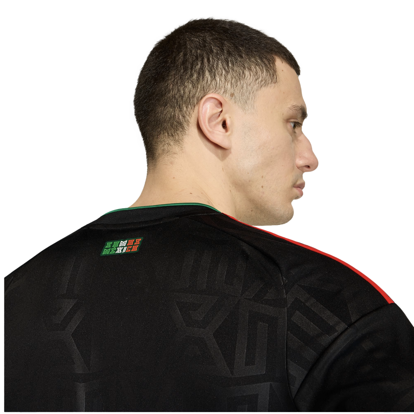 Rear profile of a man wearing a black Mexico soccer jersey with red shoulder stripes and "SOMOS MÉXICO" on the back neck.