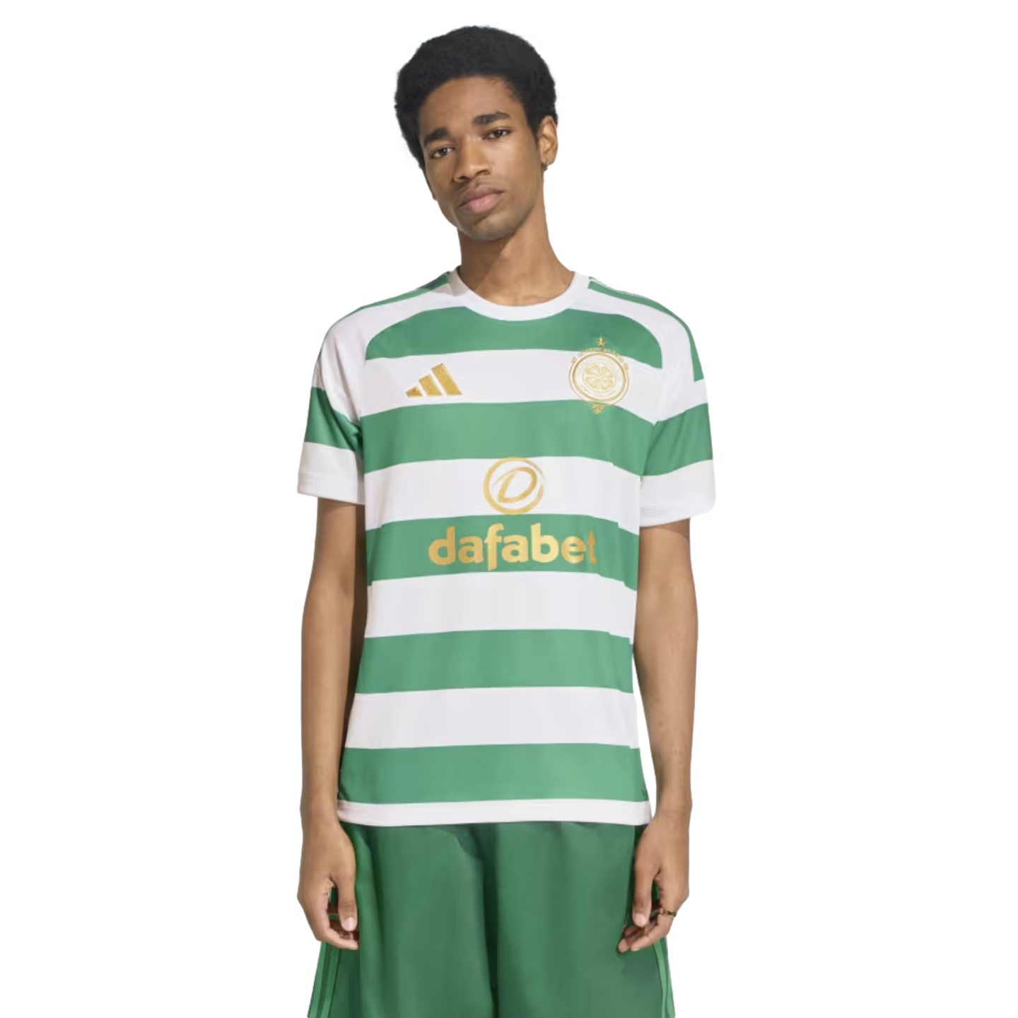 A man modeling a green and white hooped Celtic FC football jersey with gold logos and matching green shorts.