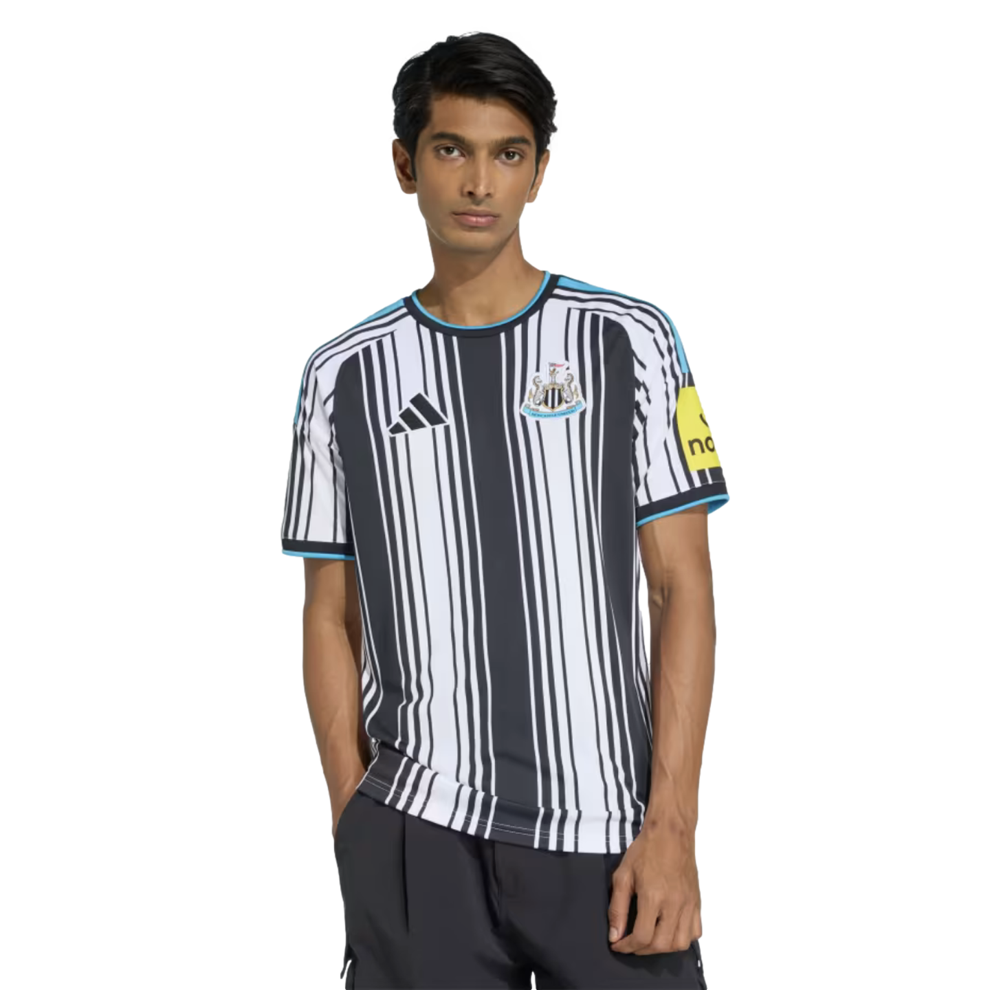 A man wearing a black and white striped Newcastle United soccer jersey with light blue accents, standing against a white background.